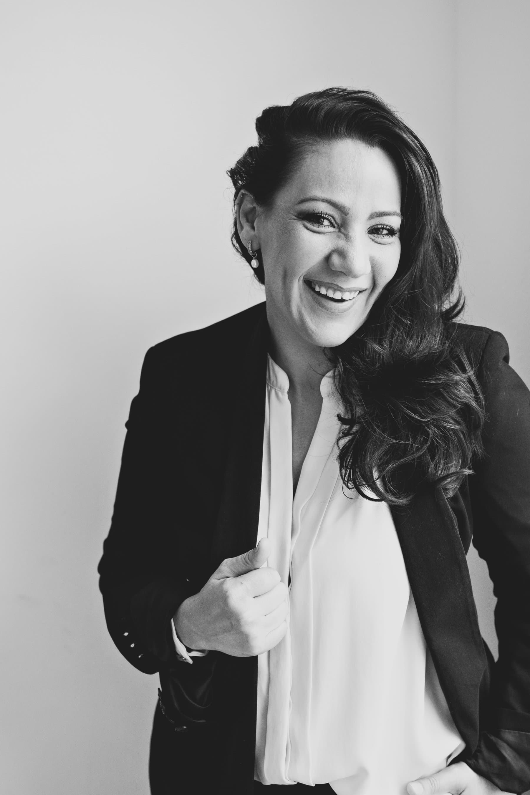 A smiling woman with long dark hair in a black blazer